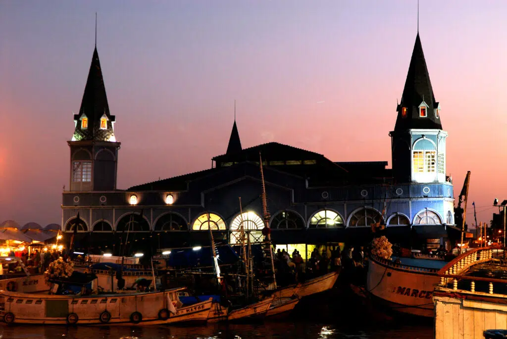 Coucher de soleil coloré au marché Ver-o-Peso, avec des bateaux de pêche amarrés près de la baie de Guajará à Belém do Pará, en Amazonie, dans le nord du Brésil.  Emblème de la ville de Belém (nord-est du Brésil), le marché Ver-o-Peso fonctionne 24 heures sur 24, du lundi au dimanche. La nuit, les grossistes déchargent leurs bateaux et vendent leurs marchandises sur le quai bondé du Mercado de Ferro. À 5 heures, Belém s’éveille, mais c’est déjà l’heure de pointe autour du marché de fer, où l’activité bat son plein.